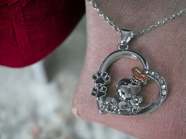 silver puppy in a heart pendant on a pink cushion