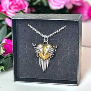 gold heart wrapped in angel wings in a black jewellery box