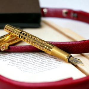 Luxury gold dragon head fountain pen on a background of an open book and a red belt