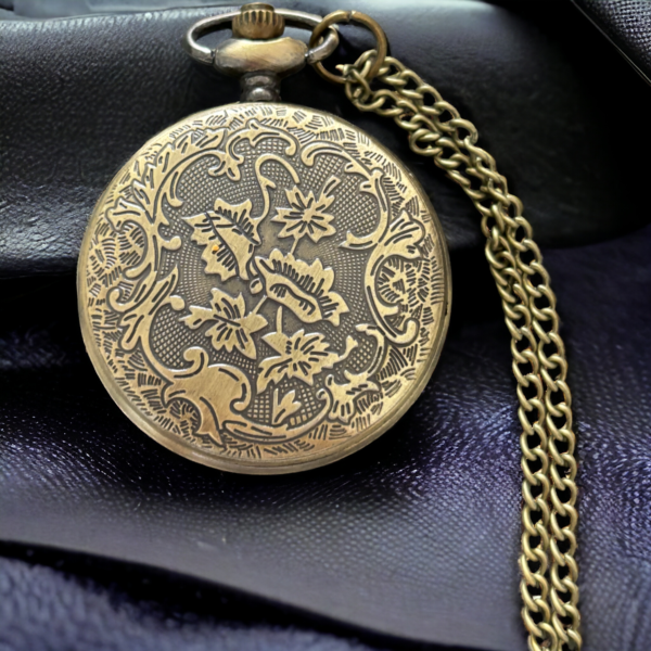 An intricate design on the back of a masonic pocket watch lying on a black cloth.