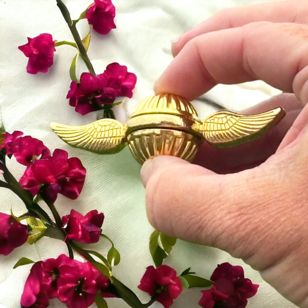 golden snitch being held on a background of cherry blossoms