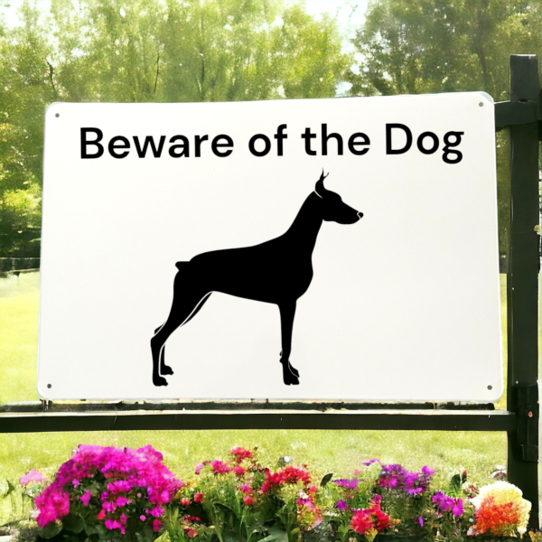 White sign with Beware the dog written on it and a picture of a dog