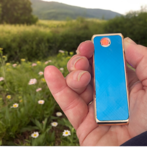 A hand holding a coil lighter with a field in the background